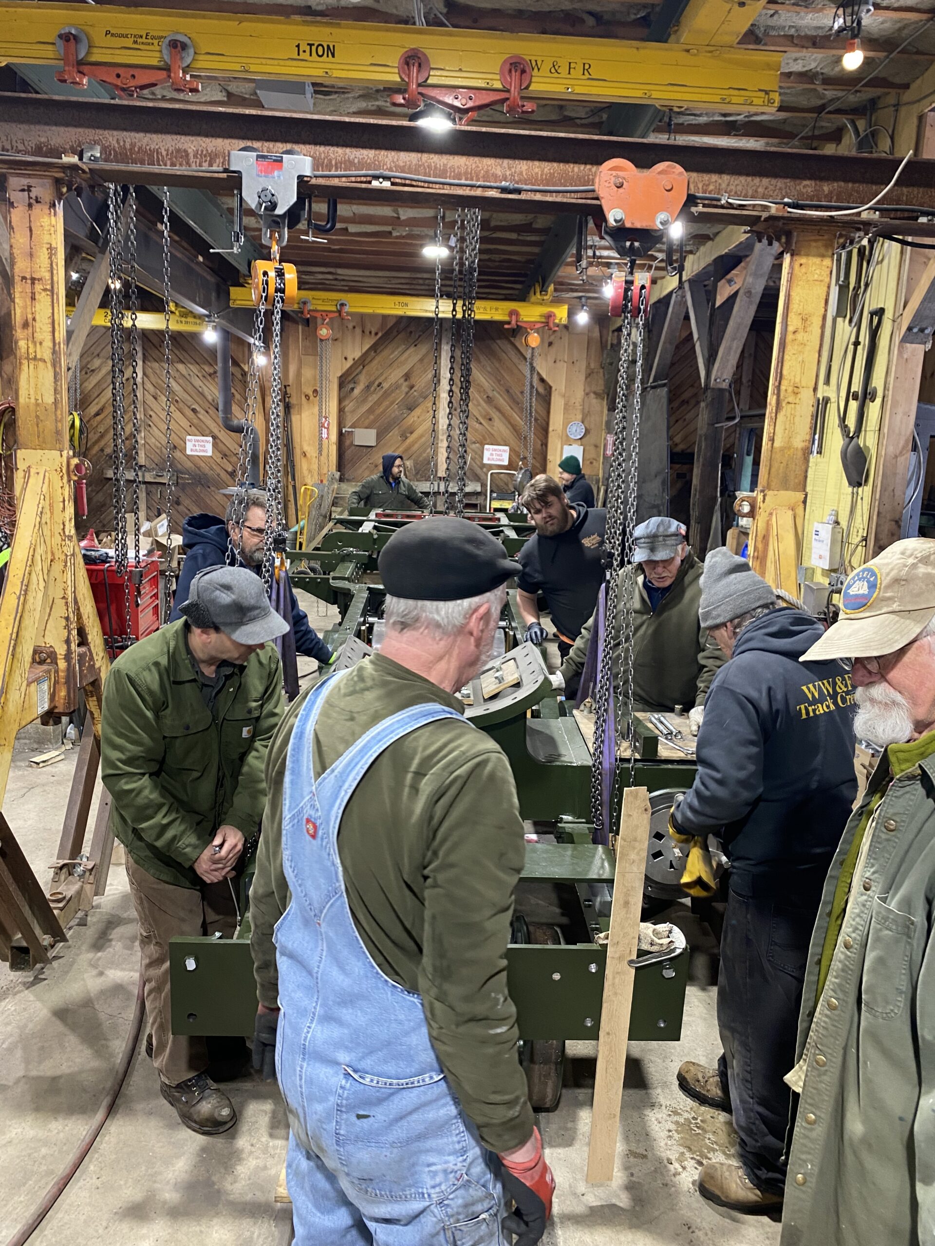 The volunteers of the WW&F Railway Museum in Alna, Maine slowly lower the frame of new steam locomotive 11 onto its wheels.