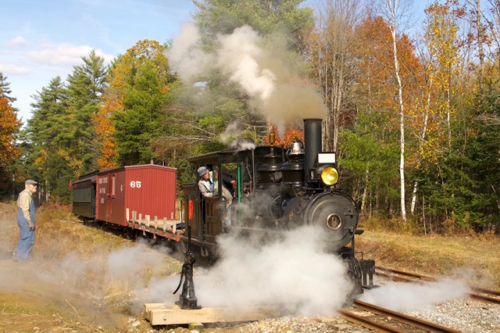 a steam engine on a train track with smoke coming out of it